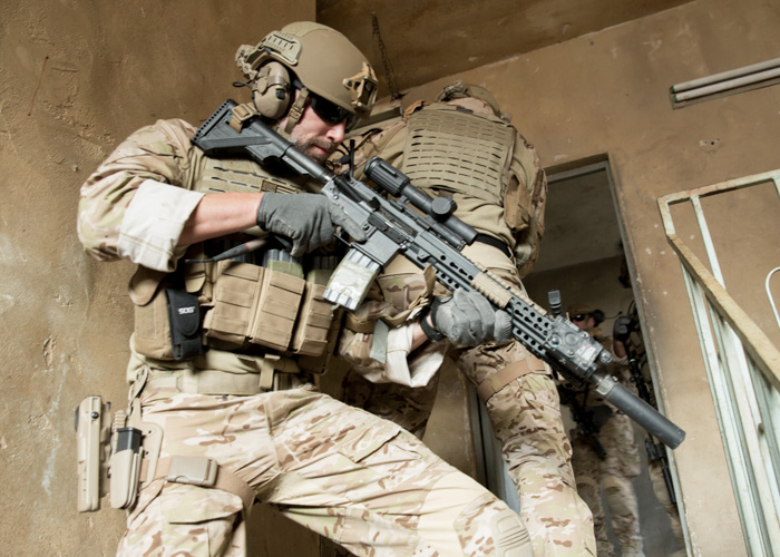 Military operative clearing stairwell wearing Safariland® armor, holster, gear and a Protech™ helmet.
