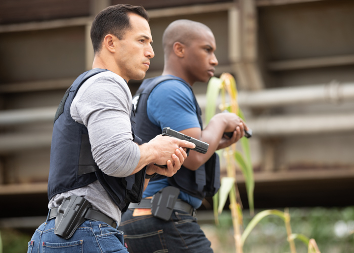 Two police detectives wearing Safariland® body armor and Safariland® and Bianchi® holsters.