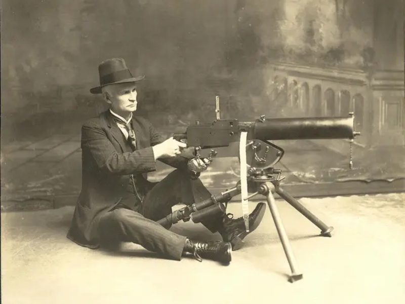 John M. Browning poses with his early water-cooled Model 1917 .30 caliber machine gun.