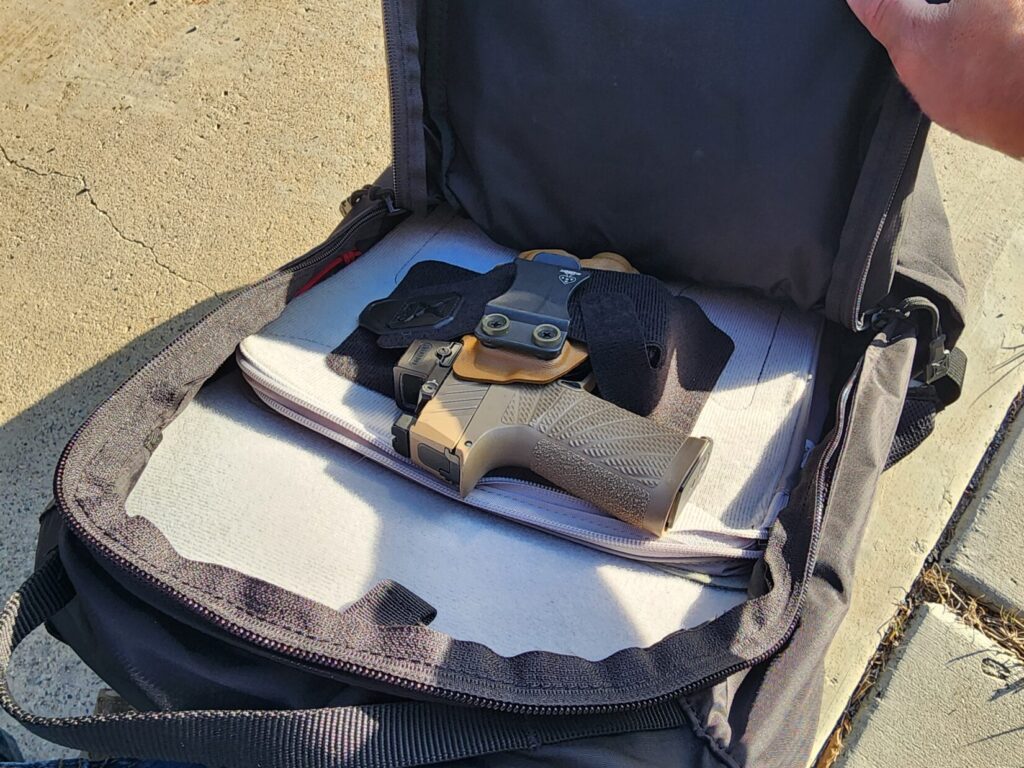 Pistol in a holster velcroed to panels inside a Vertx bag.