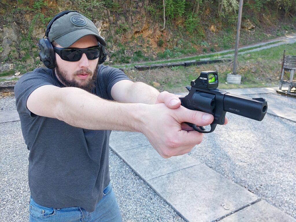 Man firing a Taurus Defender 605 TORO Revolver with Holosun optic