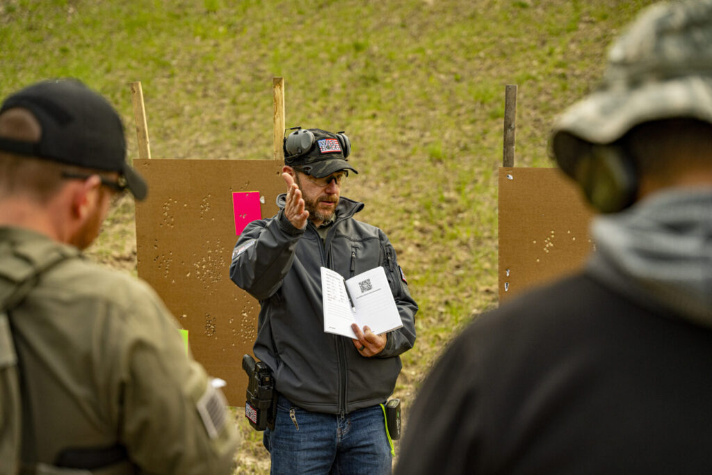 Rick Hogg holding a copy of the firearms training notebook explaining to students how to use the notebook