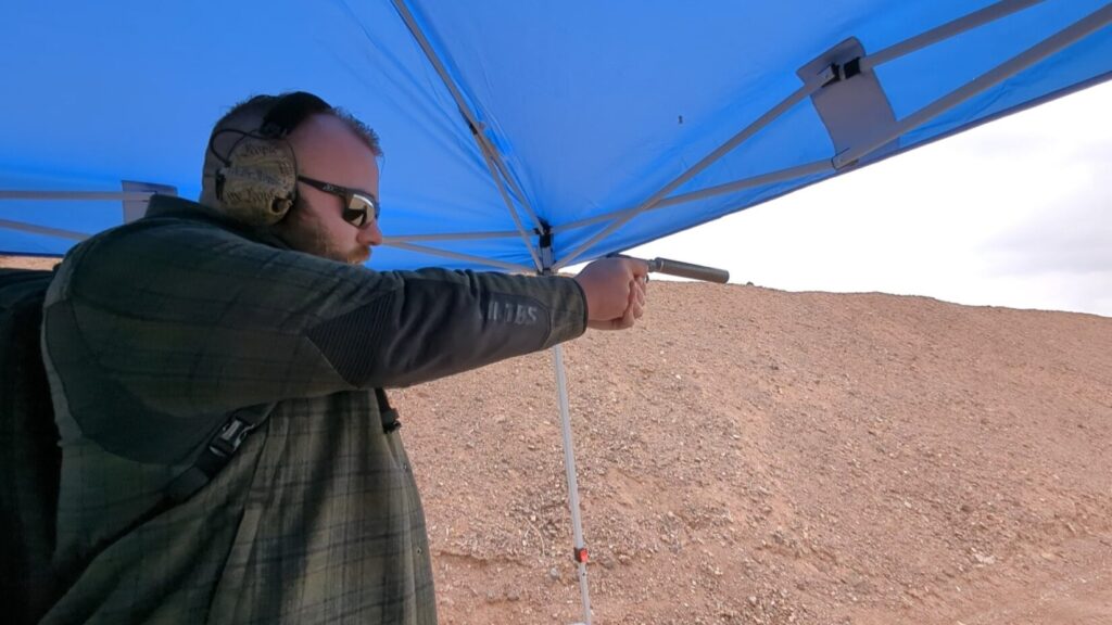 Man wearing Safariland Liberator HP 2.0 We the People headset, shooting a pistol with a silencer