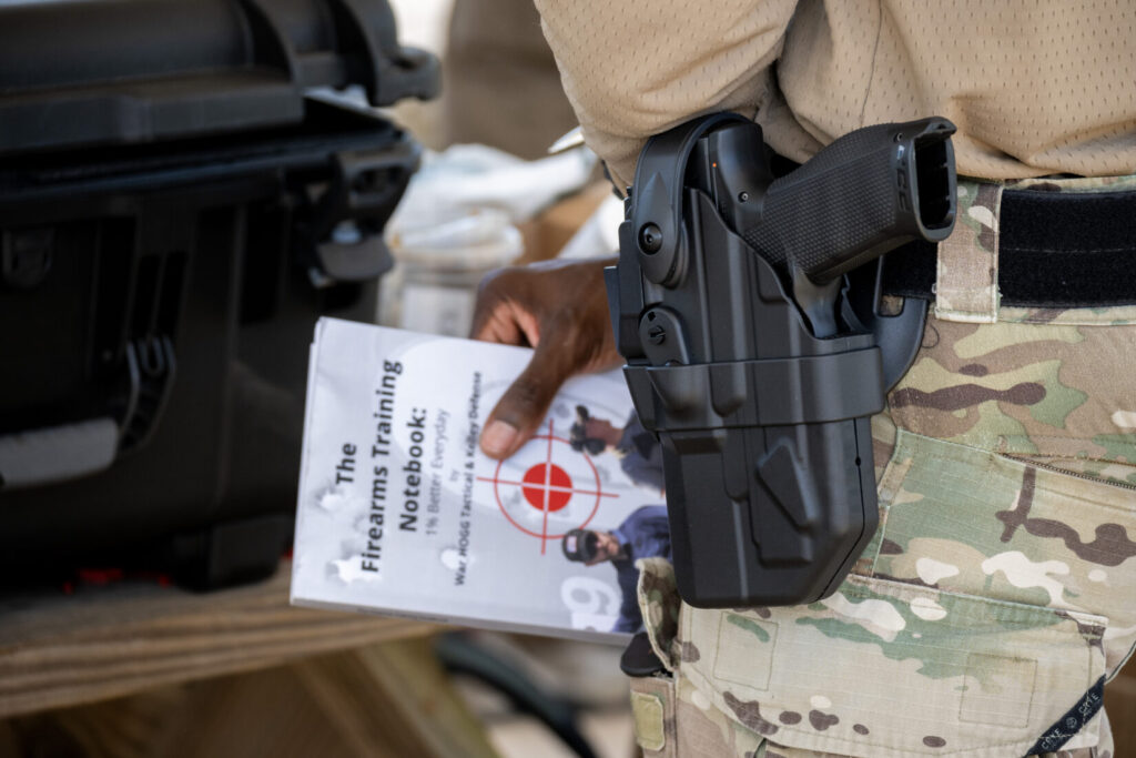 in this photo a student holds a copy of the firearms training notebook with a holstered walther pdp