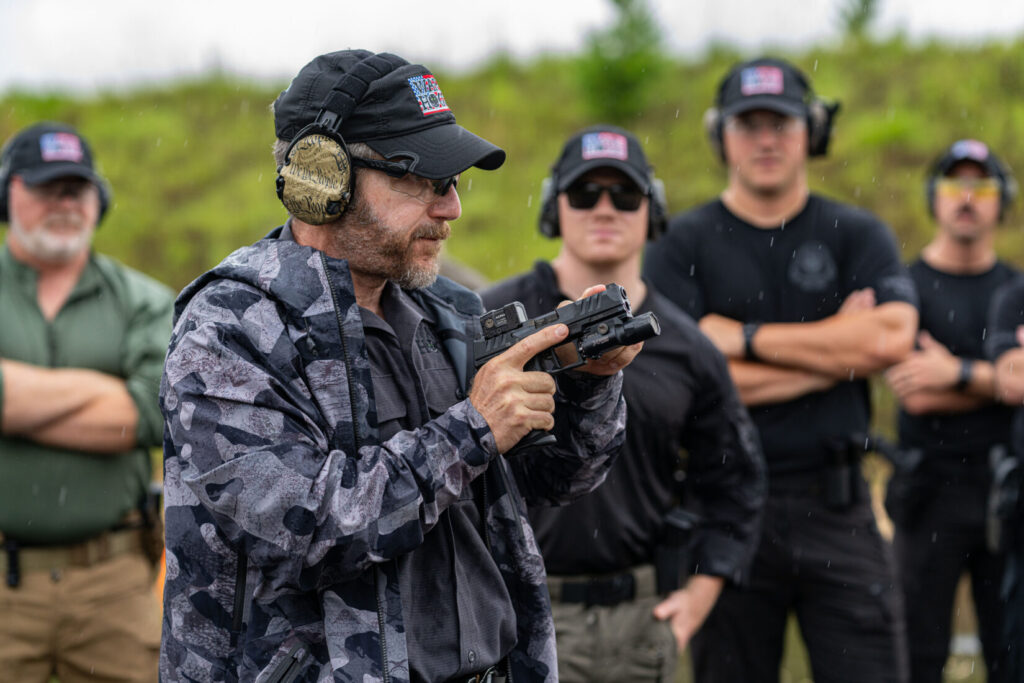 Rick Hogg is explaining to law enforcement officers about using the front sight post as a reference when presenting a red dot equipped pistol