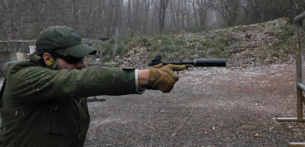 man firing a suppressed pistol