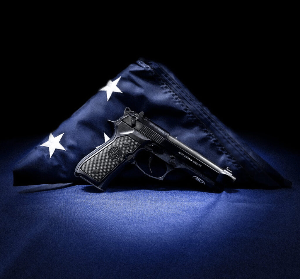 Last Beretta M9 produced, in front of a folded American flag.