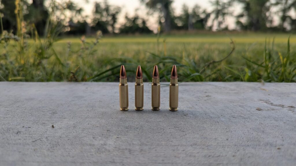 four 5.7mm rounds standing on a concrete pad, grass and trees in the background