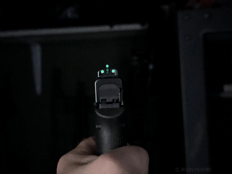 Tritium night sights (green) on glock handgun, in low light.