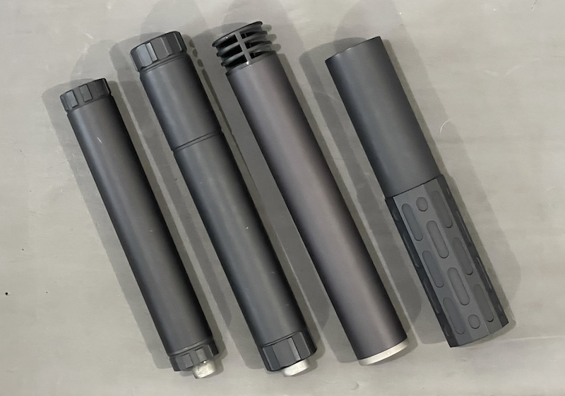 four suppressors laying on a table
