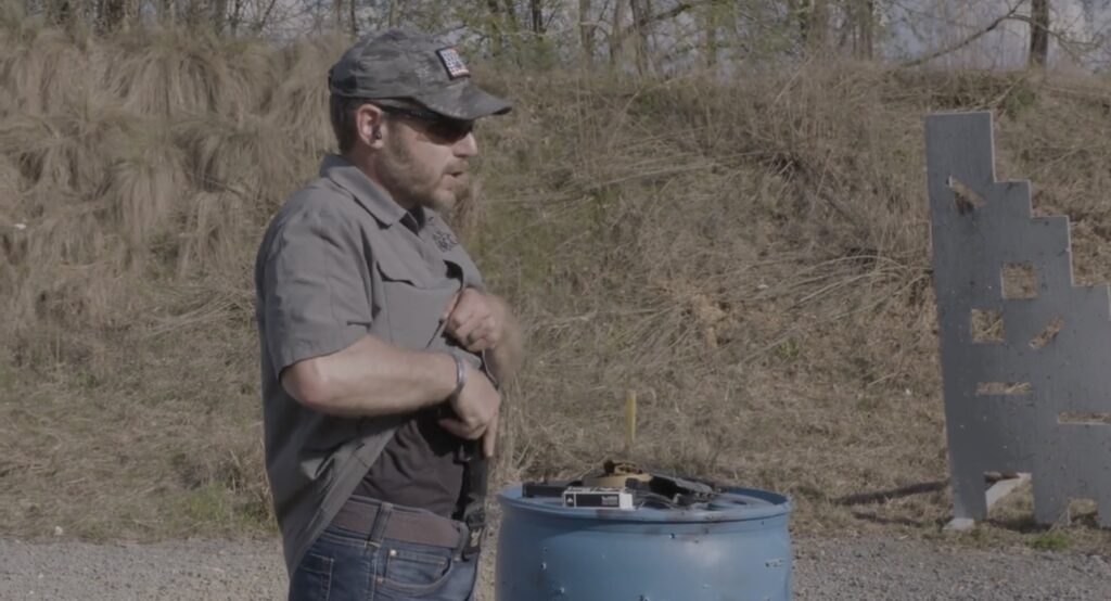 In this picture is a side view of Rick Hogg from War HOGG Tactical demonstrating drawing from concealment from an appendix carry position.