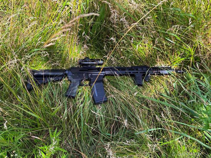 Black AR-15 in the grass.