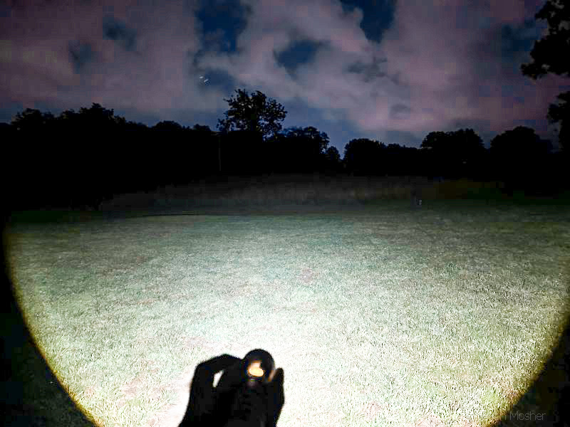 The Slyde King has a wide light pattern. image of flashlight beam pattern in a yard at night