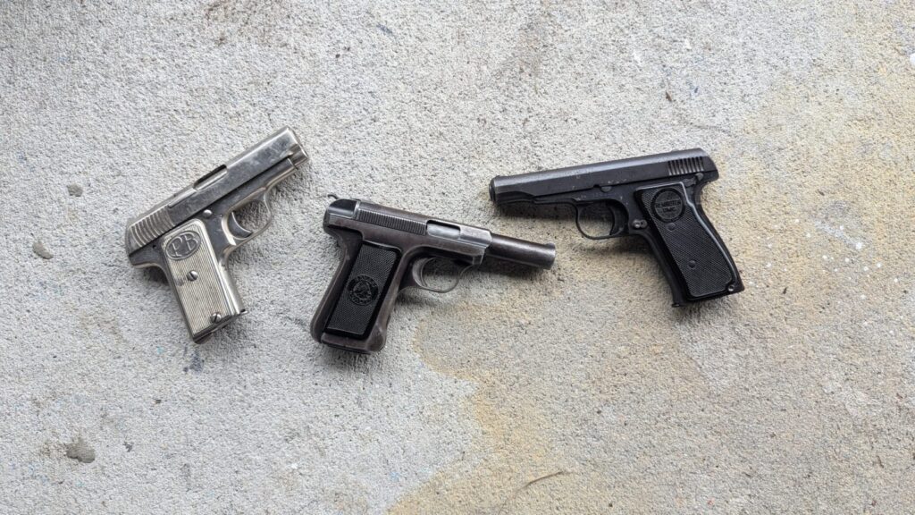 Three vintage pistols on concrete.