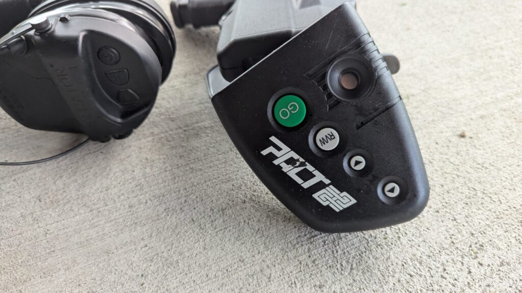 Close-up of a PACT Club Shot Timer 3 and ear protection on concrete.