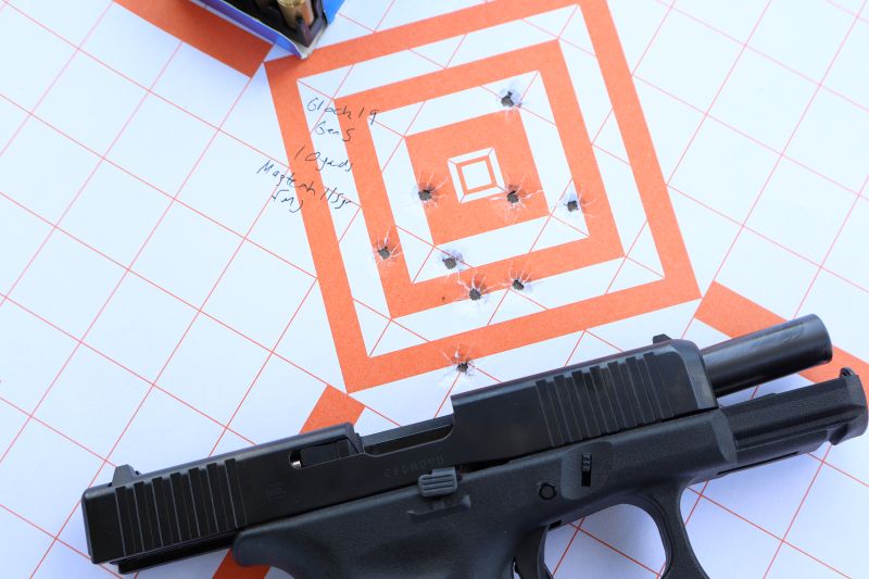 Glock 19 Gen 5 pistol with slide locked back on paper target showing shot group at 10-yards using Magtech 124 grain FMJ steel cased ammo