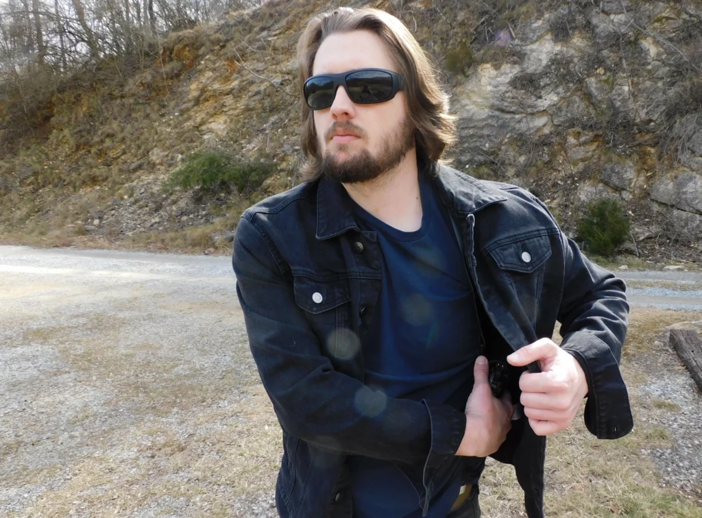 Man drawing a pistol from shoulder holster from under a jacket
