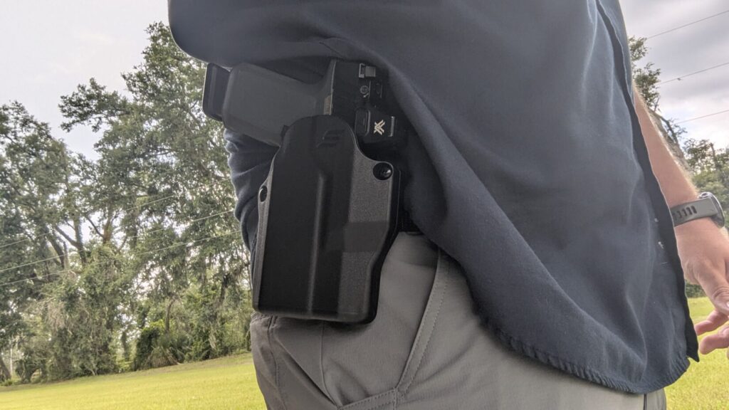 Pistol in Solis holster worn at the waist on a belt.