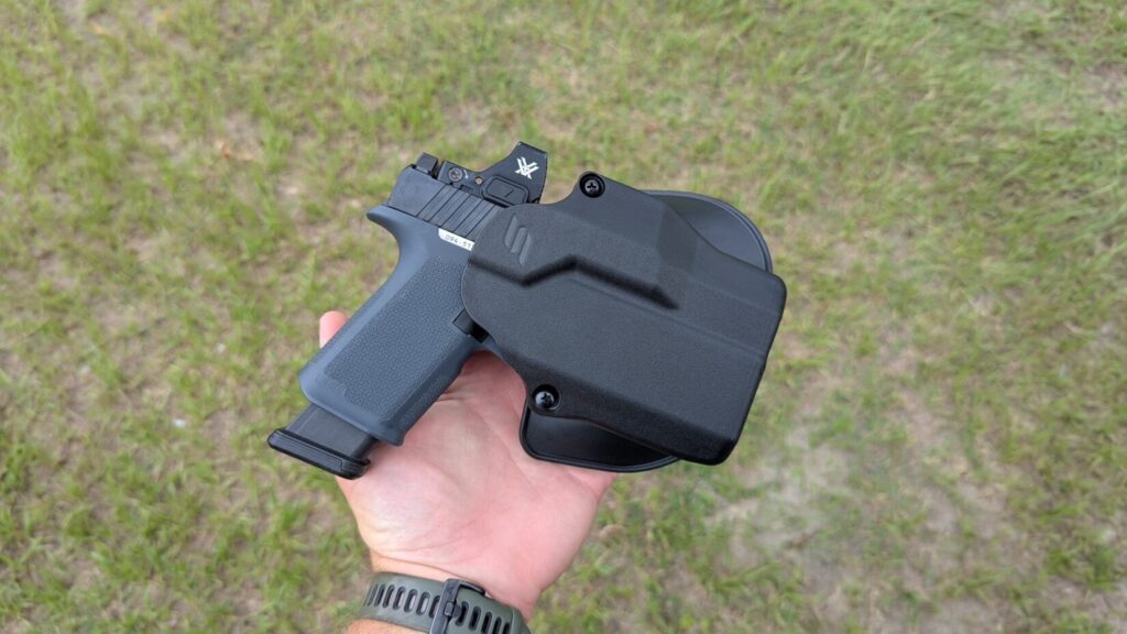Hand holding a pistol and Solis holster.