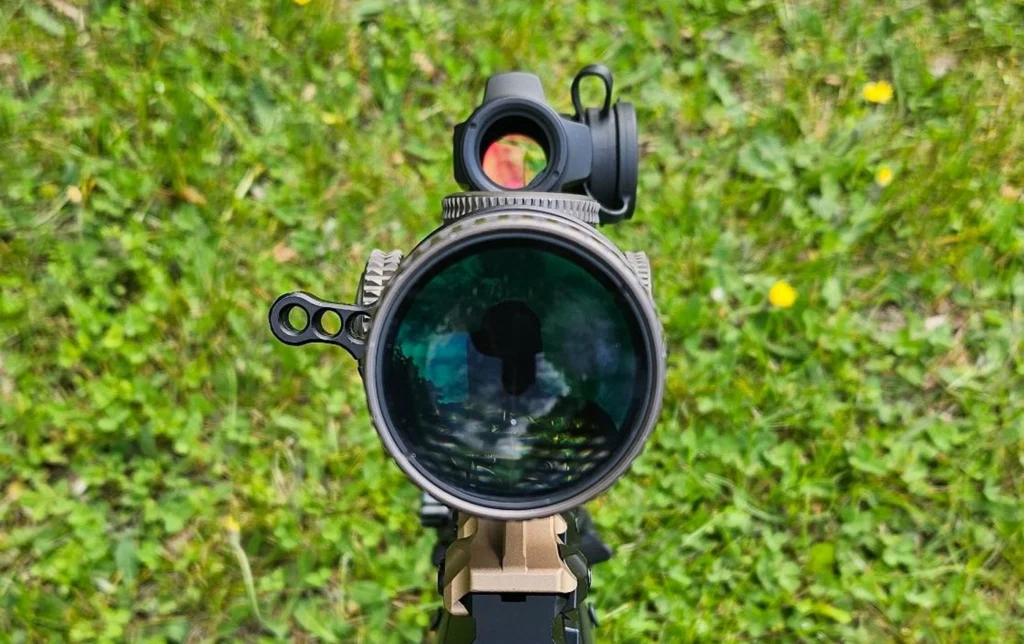 Red dot optic mounted on top of a rifle scope