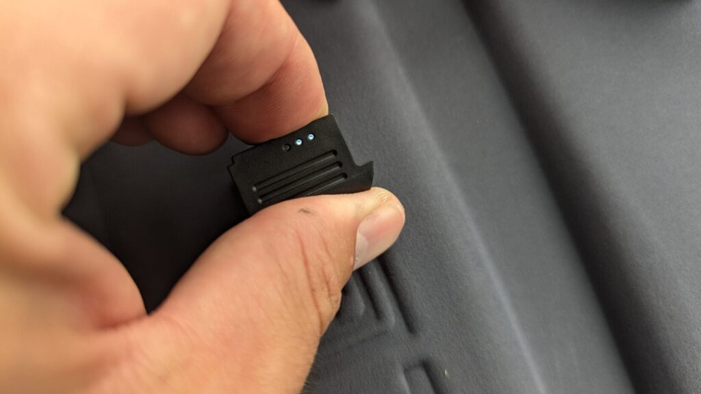 Hand holding a small proprietary B12 battery pack.