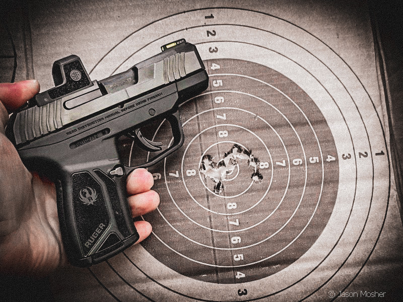 Ruger MAX-9 with Sig optic, in hand, paper target in background.