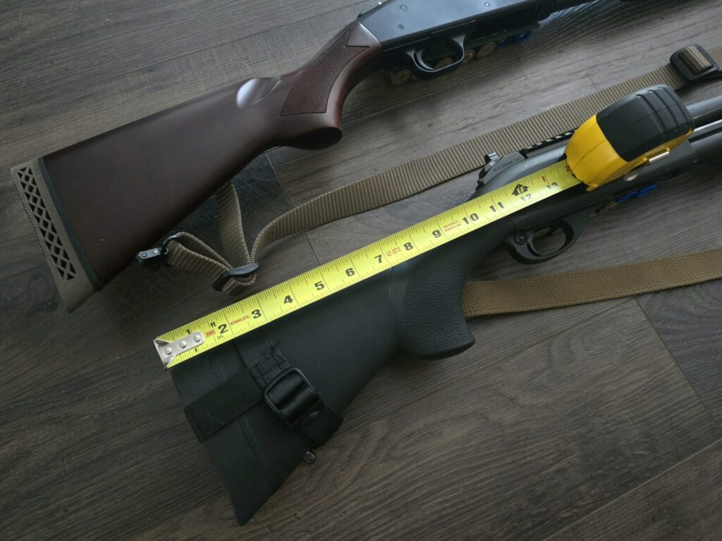 A tape measure is used to show the size of a youth model shotgun stock next to a full-length shotgun stock