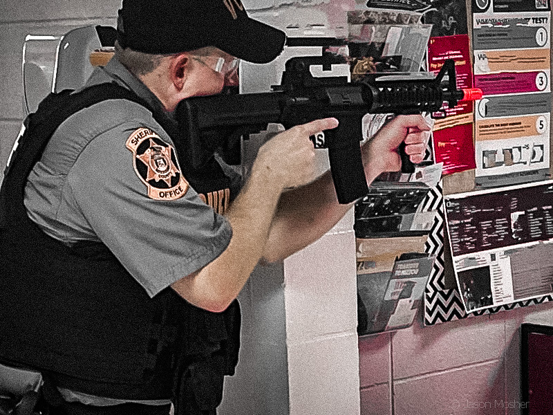 A deputy uses a brick wall as cover during a training exercise