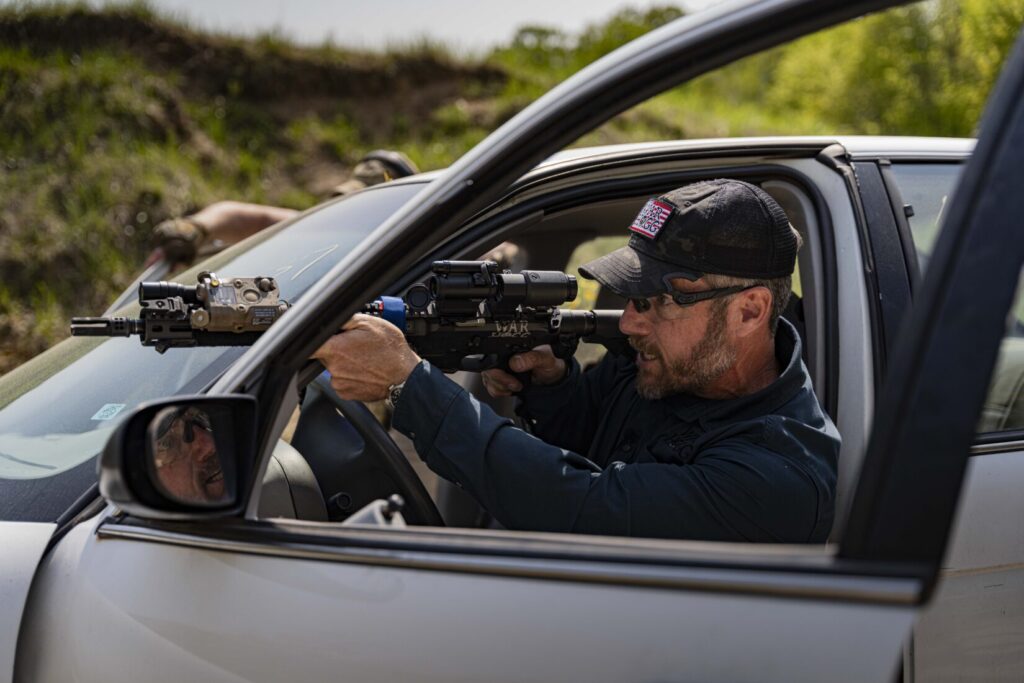 in this photo Rick Hogg of War HOGG Tactical is firing his carbine from a seated position in a vehicle through the "V" of the door and A pillar