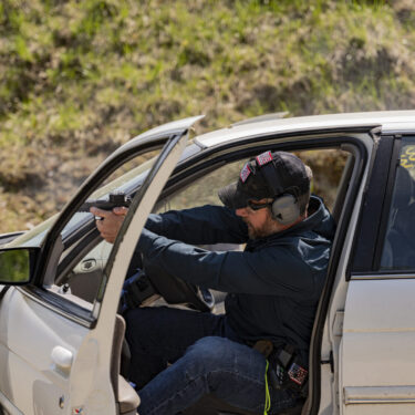 Rick Hogg of War HOGG Tactical is demonstrating to law enforcement officers how to shoot a pistol from a seated position in a vehicle