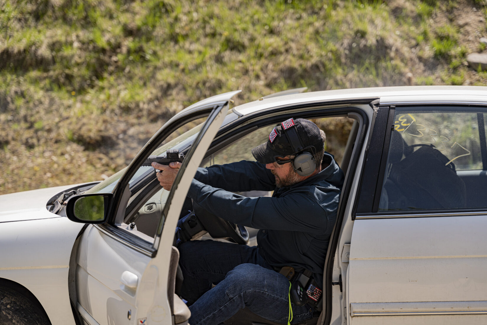 Rick Hogg of War HOGG Tactical is demonstrating to law enforcement officers how to shoot a pistol from a seated position in a vehicle