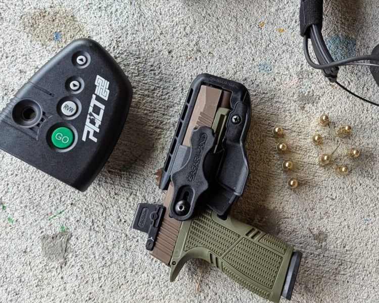 Pistol in holster, dry fire device, eye protection, ear protection, and brass cartridges.