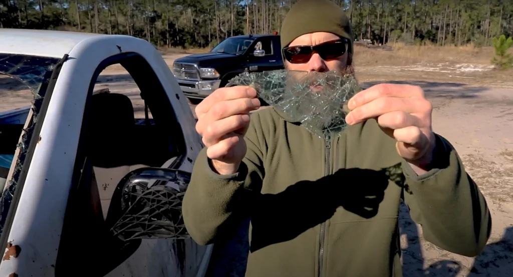 man holding shattered, spiderwebbed windshield glass