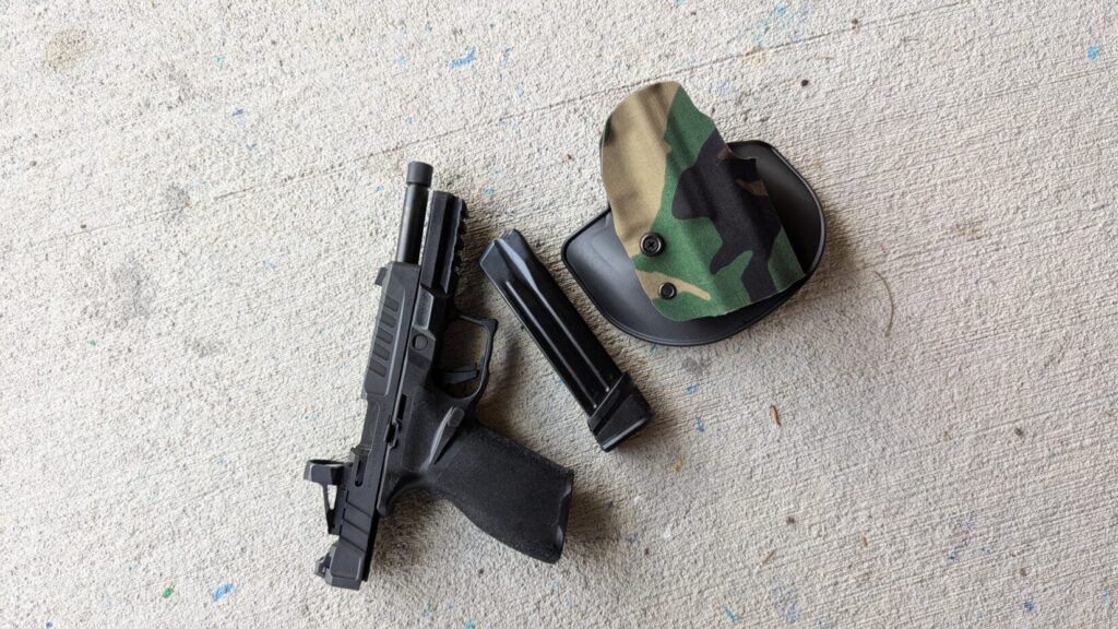 Green/tan pistol (slide locked), magazine, black holster, dry fire device.