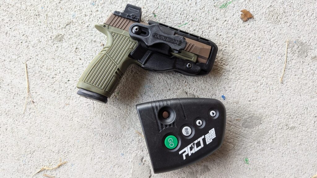 Green/tan pistol with Holosun red dot in Safariland Schema holster, shot timer.