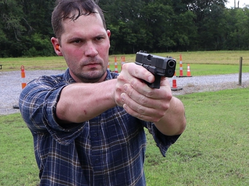 man wearing plaid flannel shirt shooting the glock 19 gen 5 pistol outdoors