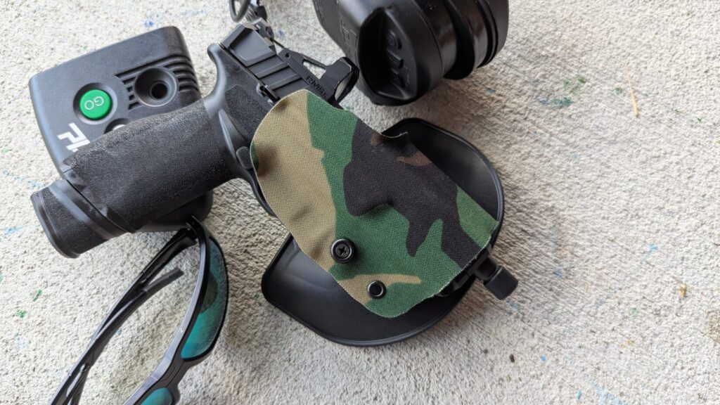 Black pistol and Gravity holster on concrete.