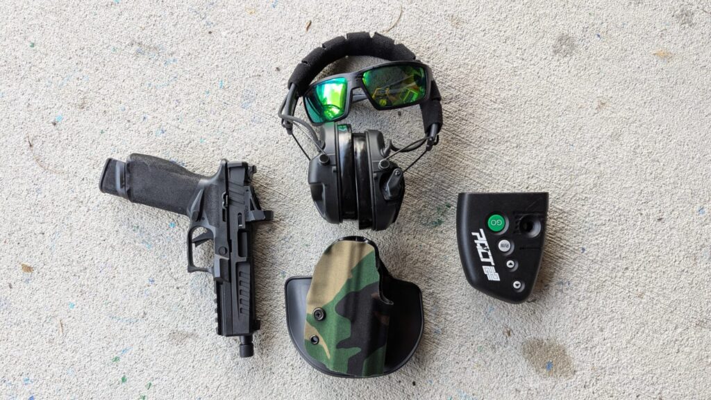 Black pistol in M81 pattern camo holster, with eye protection and dry fire device.