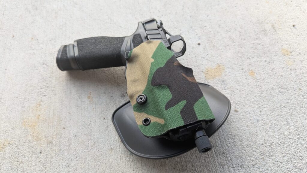 Black pistol in a black Safariland Gravity holster with camouflage fabric.