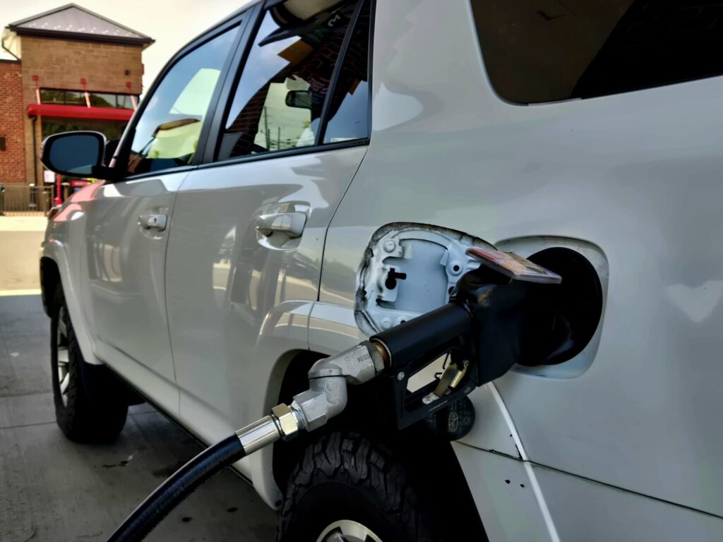 White SUV gassing up. Refueling at the half-tank ensures the vehicle has more range.