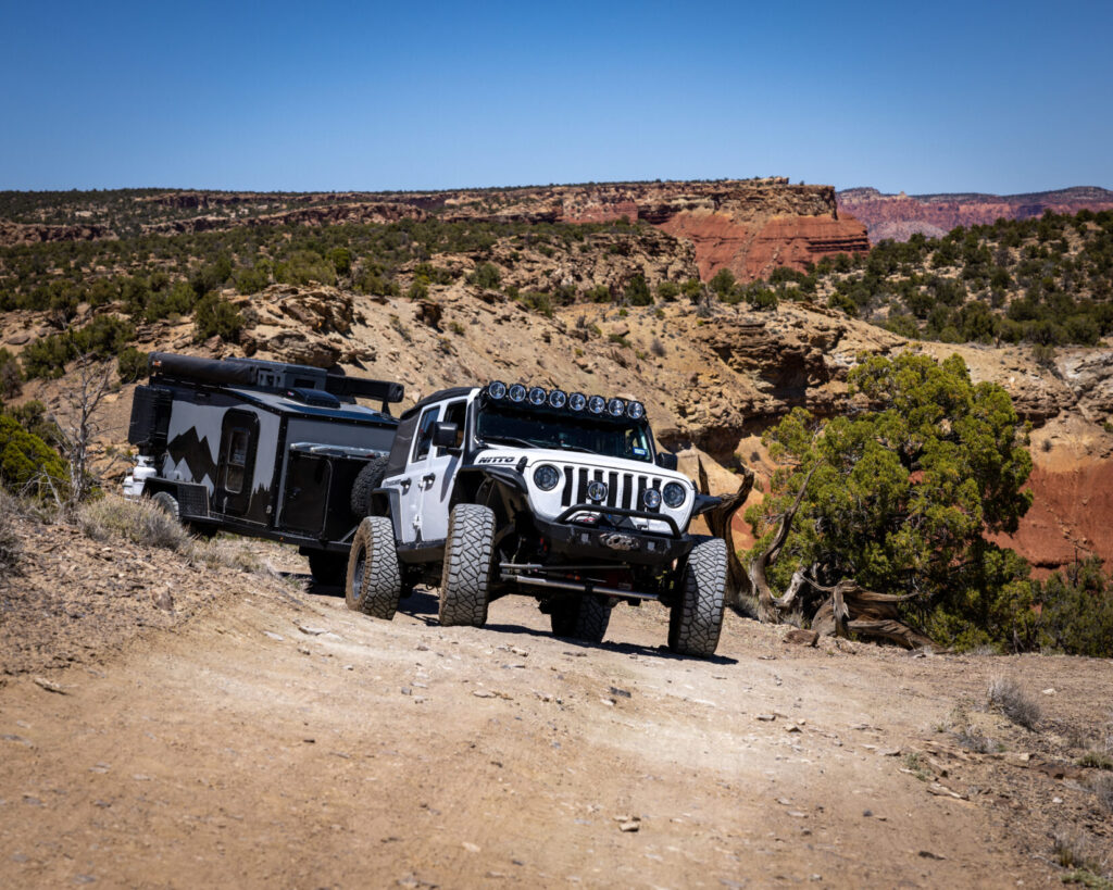 Overland Jeep rounding a corner in a desert landscape with equipment for the backcountry