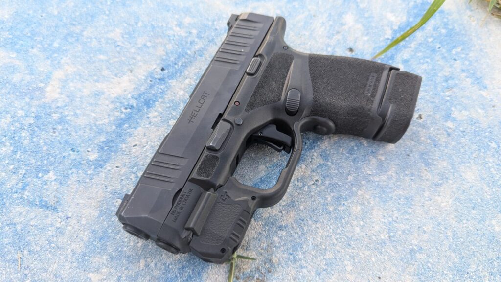 A black Hellcat pistol resting on a light blue and white textured surface.