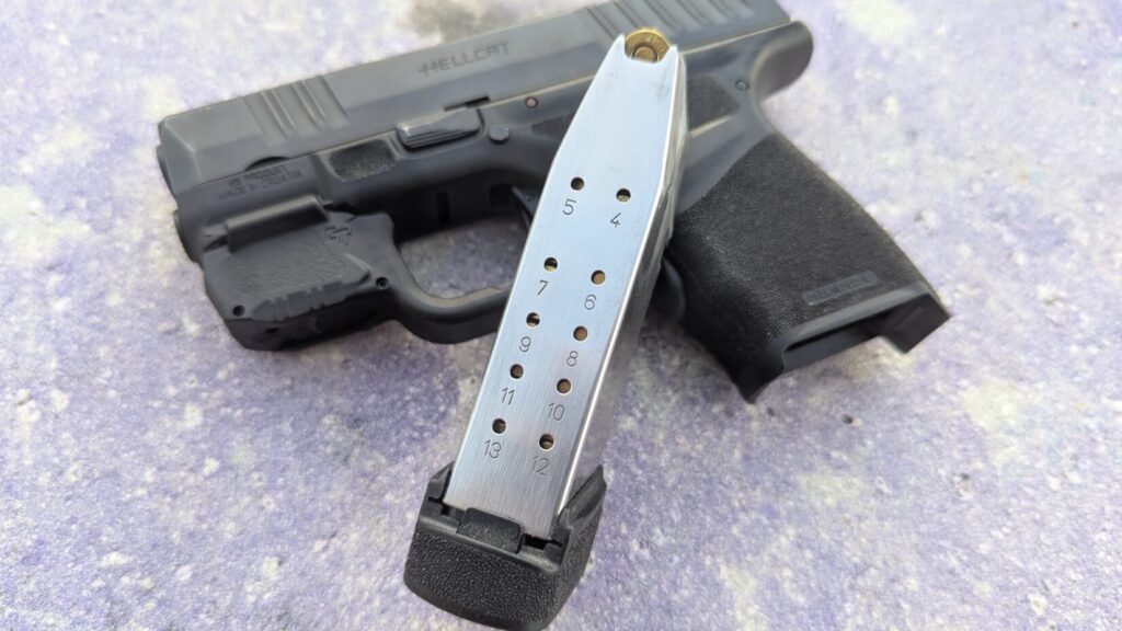 A Hellcat pistol with a magazine lying on top of it, showing bullet indicators from 4 to 13.