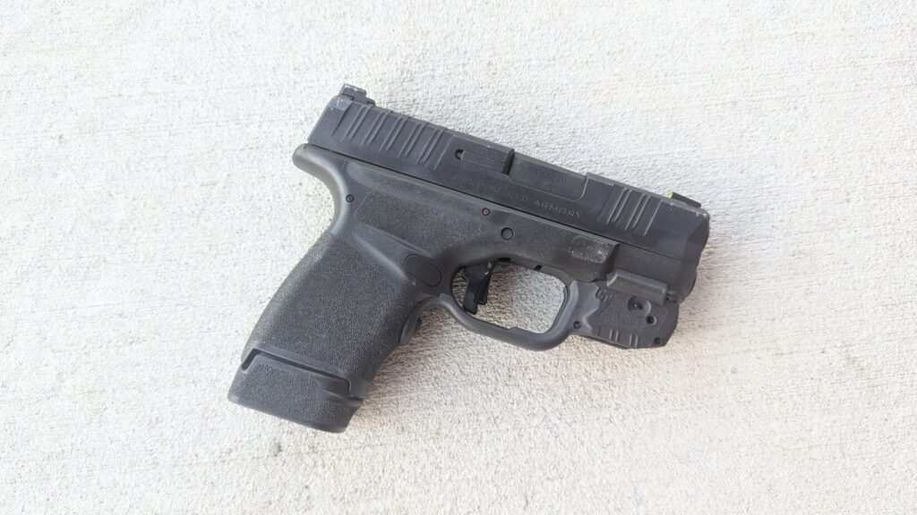 A black Hellcat pistol resting on a concrete surface.