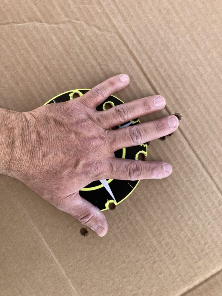 Over 20 rounds of big bore revolver shots on cardboard covered by a hand