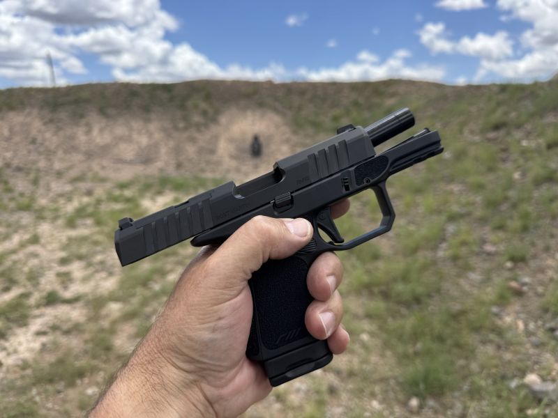 hand holding Rost Martin RM1S Subcompact with slide locked back. It is a very accurate pistol. This steel plate was hit multiple times from 50 yards. This is good performance from a smaller handgun.