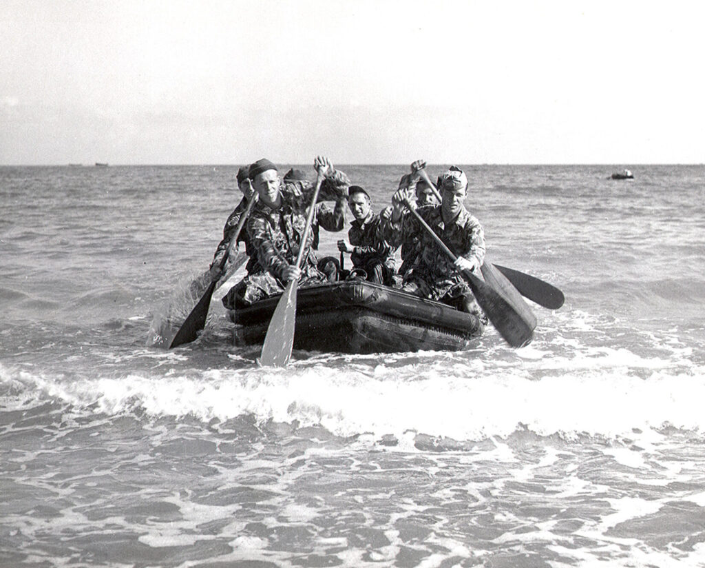 black and white photo of Raider team rowing in a boat. Formed at ATB Little Creek, VA, the unit, composed of Army and Navy personnel under Army 1st Lt. Lloyd Peddicord and Navy Ens. John Bell,trained for Operation Torch, the Allied invasion of North Africa in November 1942. Four months later, the Scouts and Raiders school was established at Ft. Pierce, FL.(U.S. Navy photo. Public Domain)