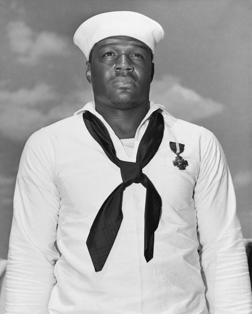 Doris "Dorie" Miller, Mess Attendant Second Class, USN, just after being presented with the Navy Cross by Admiral Chester W. Nimitz, on board USS Enterprise (CV-6) at Pearl Harbor, 27 May 1942. (Photo by Adam Cuerden - Naval History and Heritage Command. Public Domain)