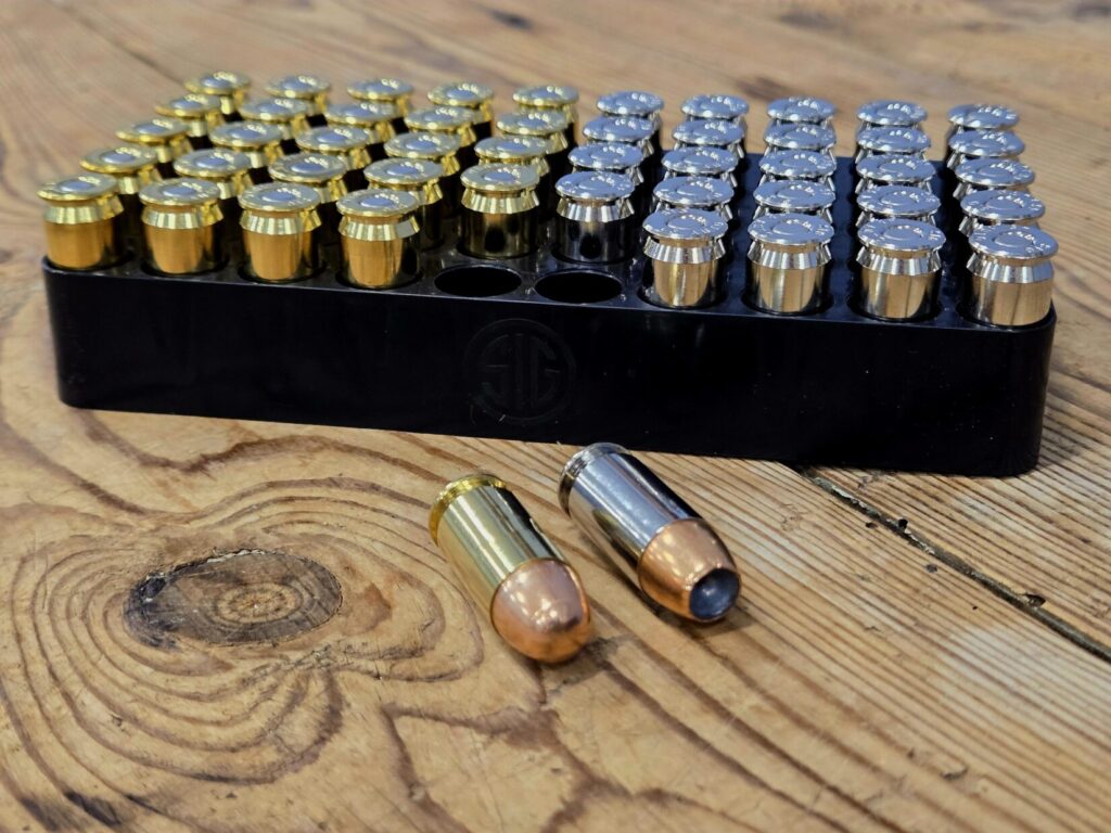 A box of 50 rounds of ammunition with two removed and on a wooden table