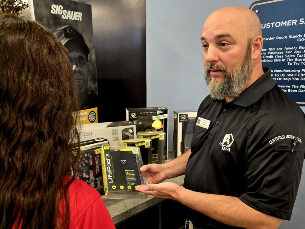 A sales associate from the Powder Room wearing a black USCCA shirt holding a lifepod safe in front of a student